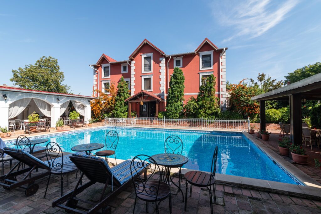 Vila roșie cu piscină și mobilier de grădină.