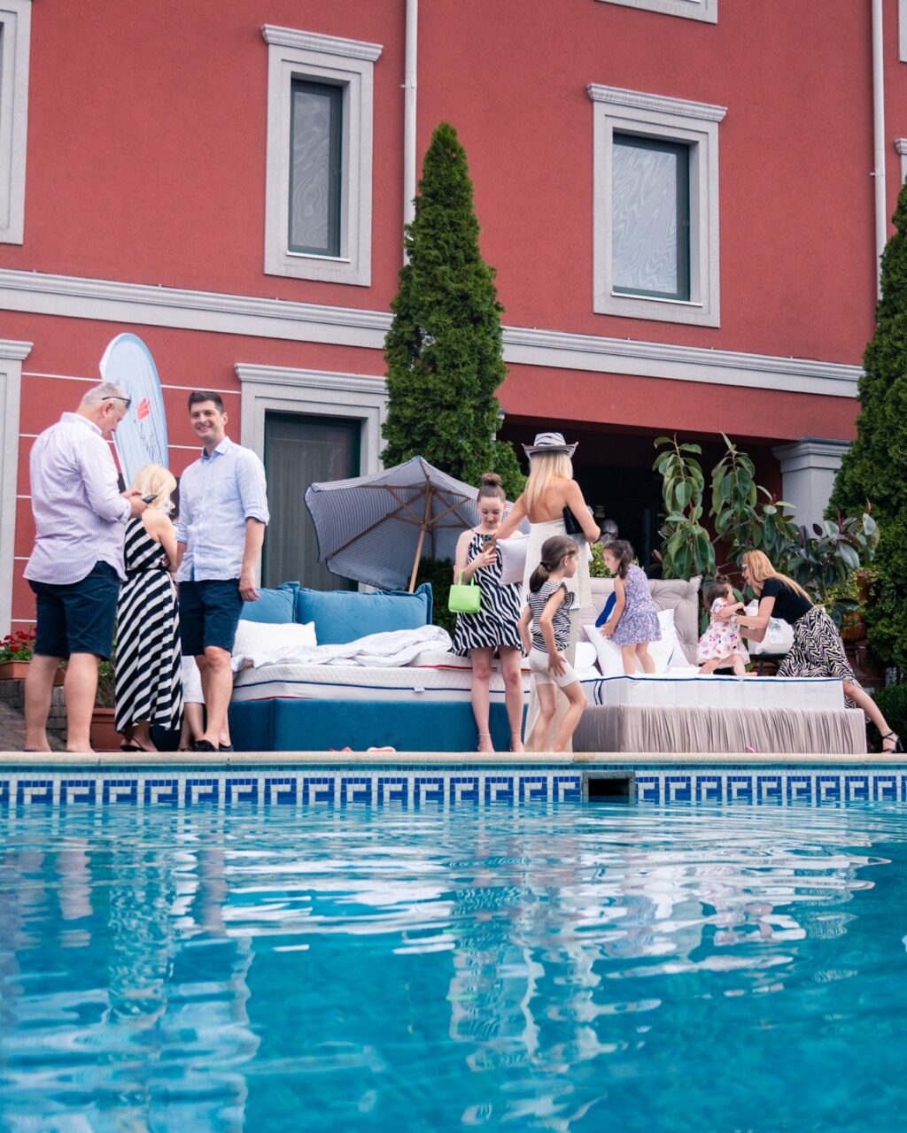 People by the pool in front of a big house.