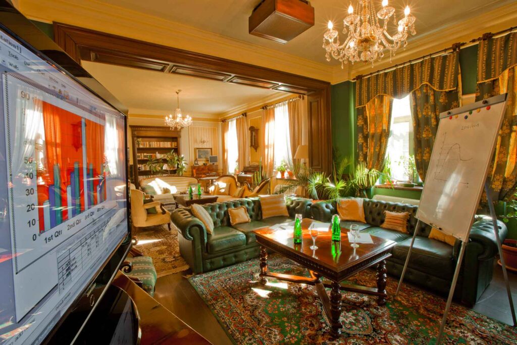 Elegant living room with green sofa and chandeliers.