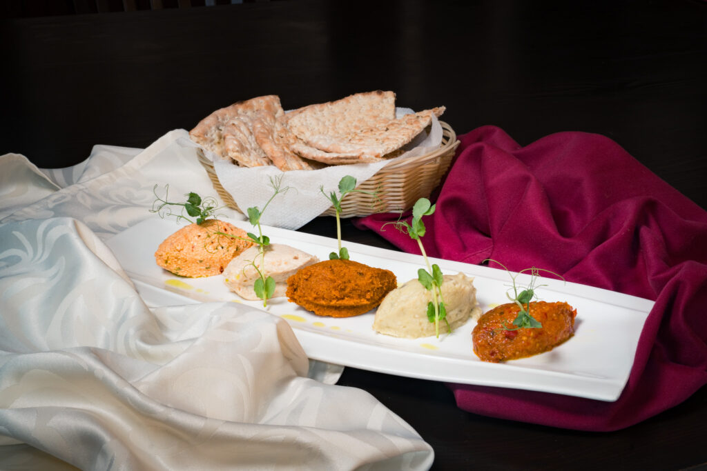 Platter with colorful spreads and bread.